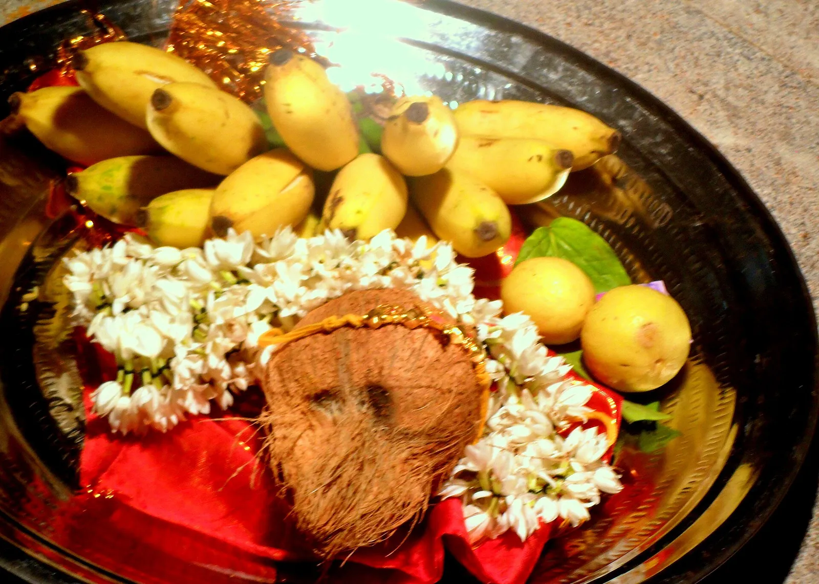 A brass plate of bananas, lemons, a coconut and jasmine flowers prepared for a wedding ritual