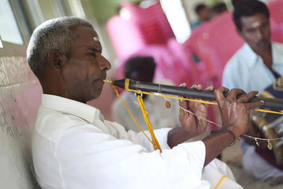 An elderly musician playing the nathaswaram at a wedding