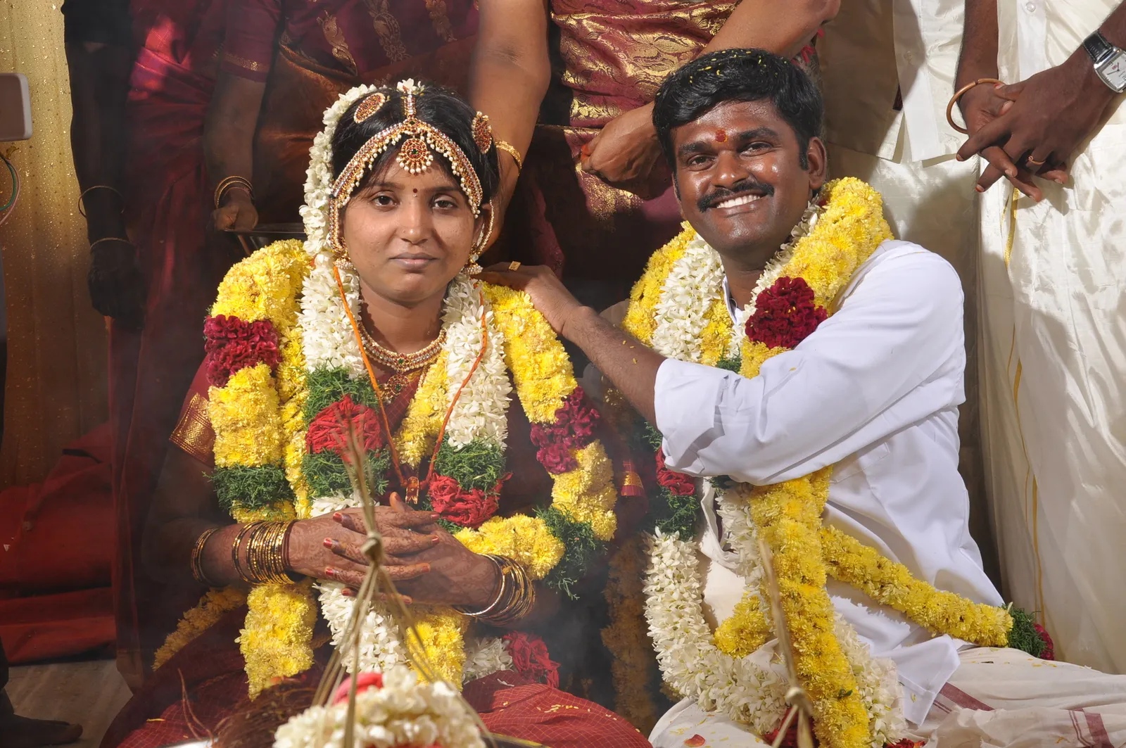 A smiling Tamil bride and groom wearing flower garlands at their wedding